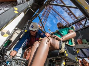 A NASA researcher assists in the preparation of a crash test dummy seated inside the Lift+Cruise model. Researchers use crash test dummies to learn how the crash impact would affect humans. Credits: Dave Bowman